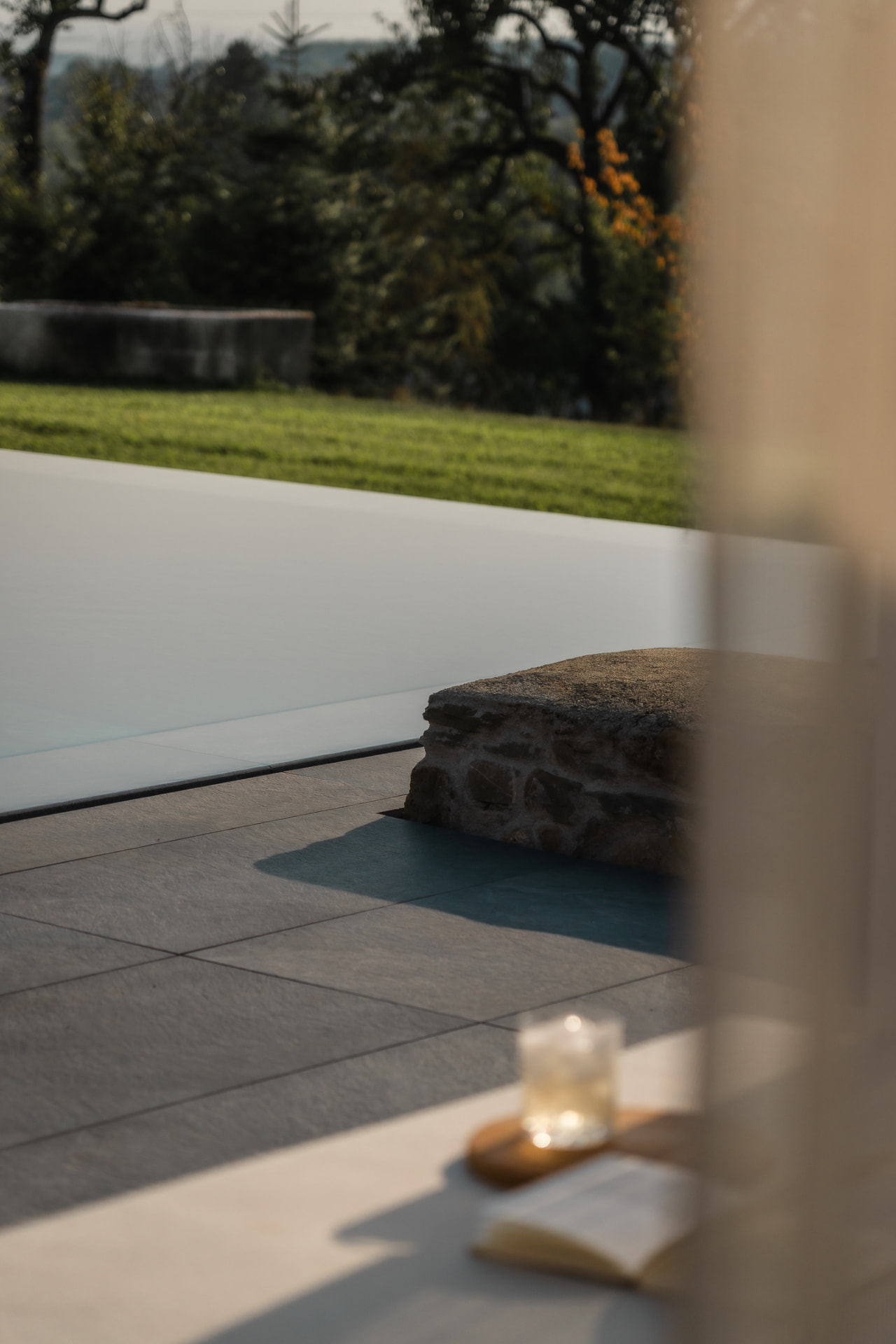 Banc en pierre ancienne au bord d'une piscine, campagne en arrière-plan